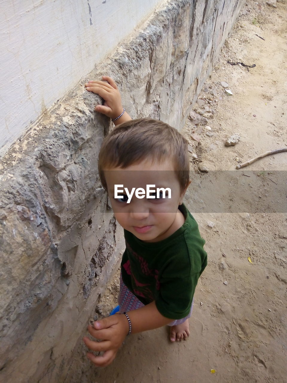 Portrait of cute boy smiling while standing against wall