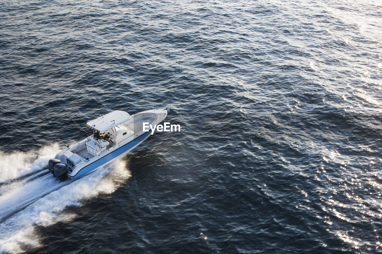 Aerial view of couple driving speedboat on sea