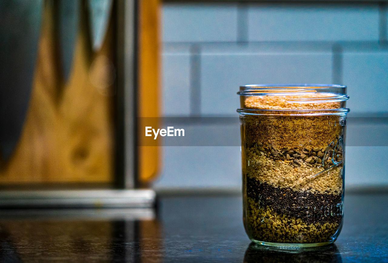 A jar of healthy granola sits on a granite counter top. 