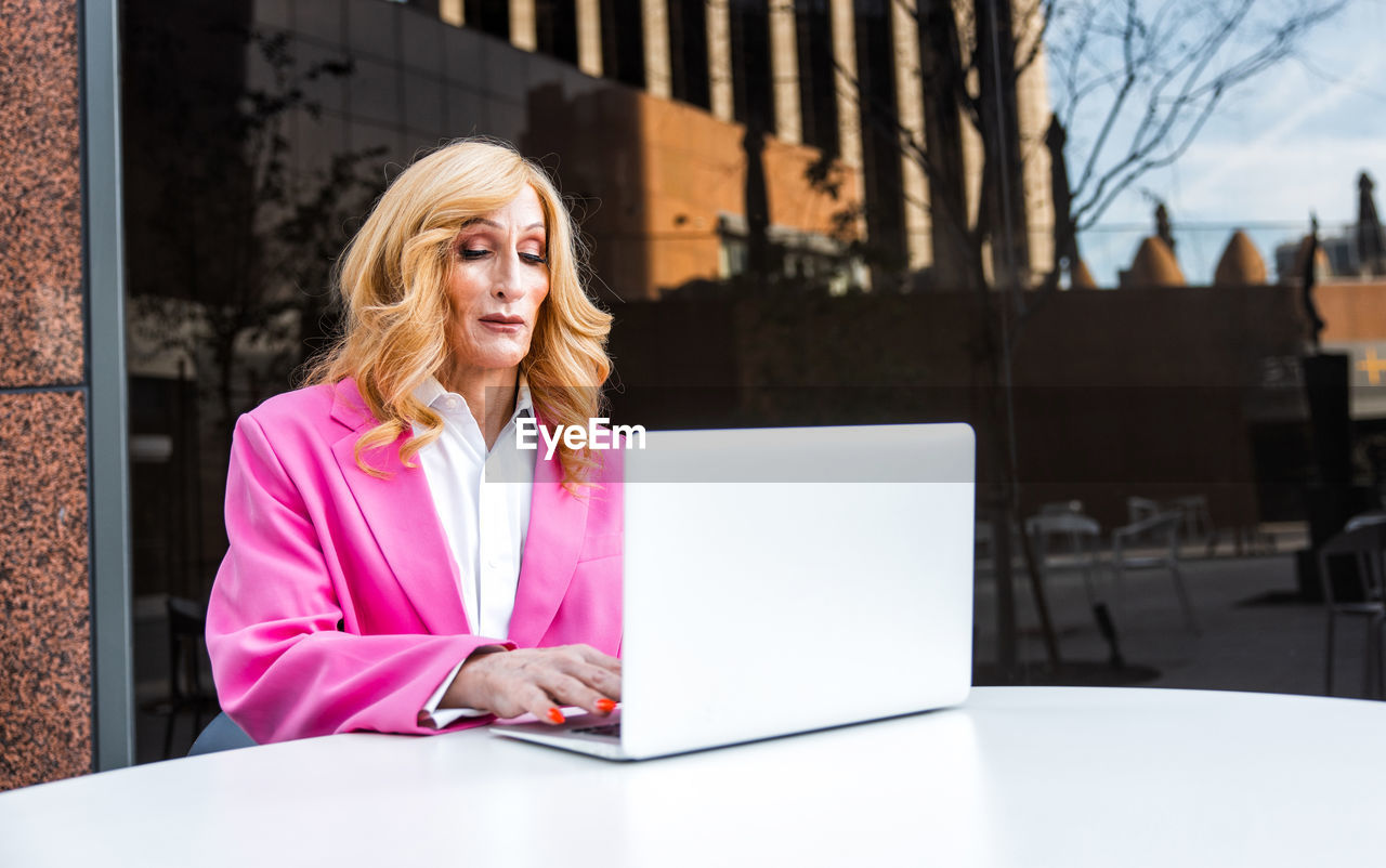 portrait of young businesswoman using laptop while sitting on table