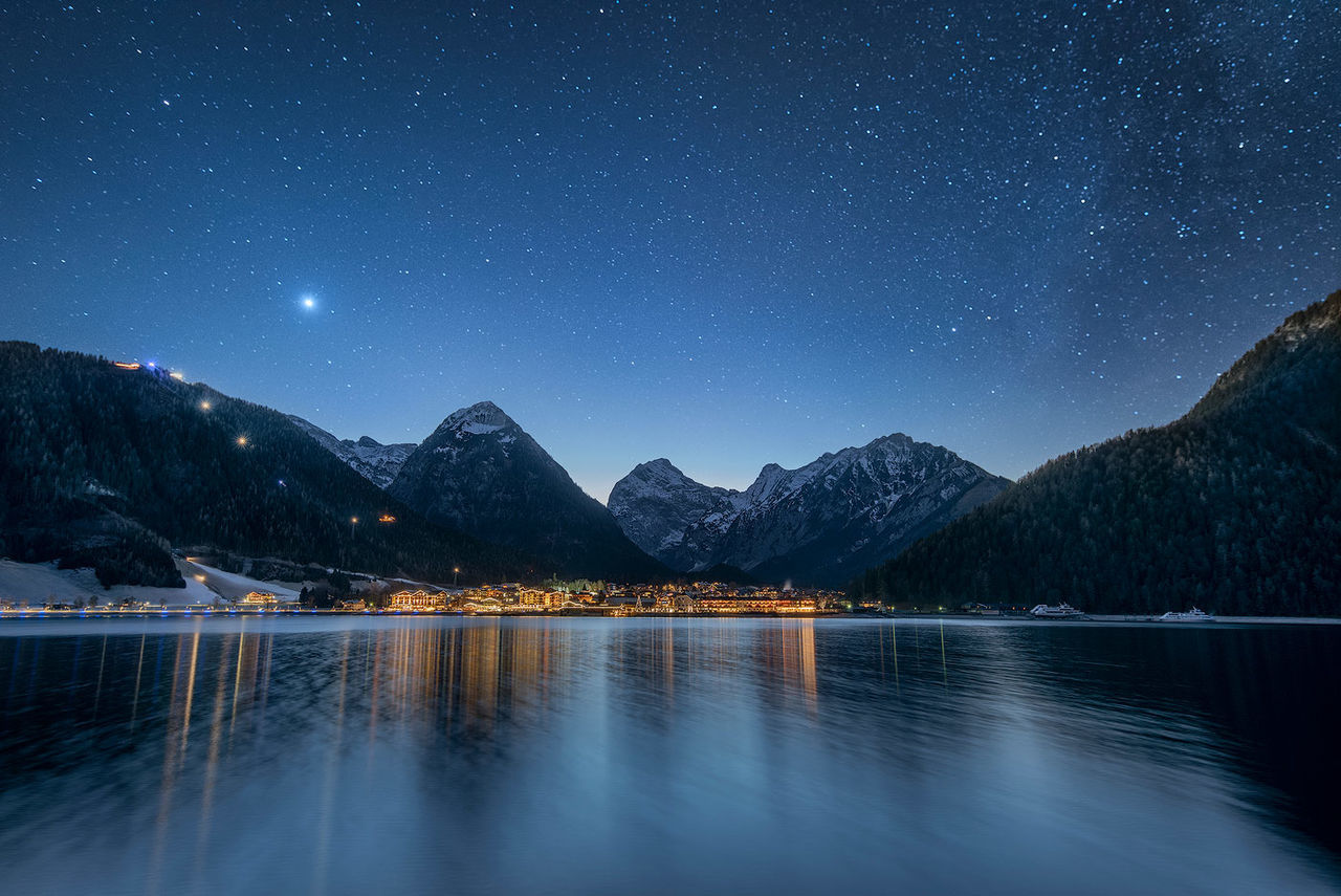 Scenic view of lake against mountain range at night