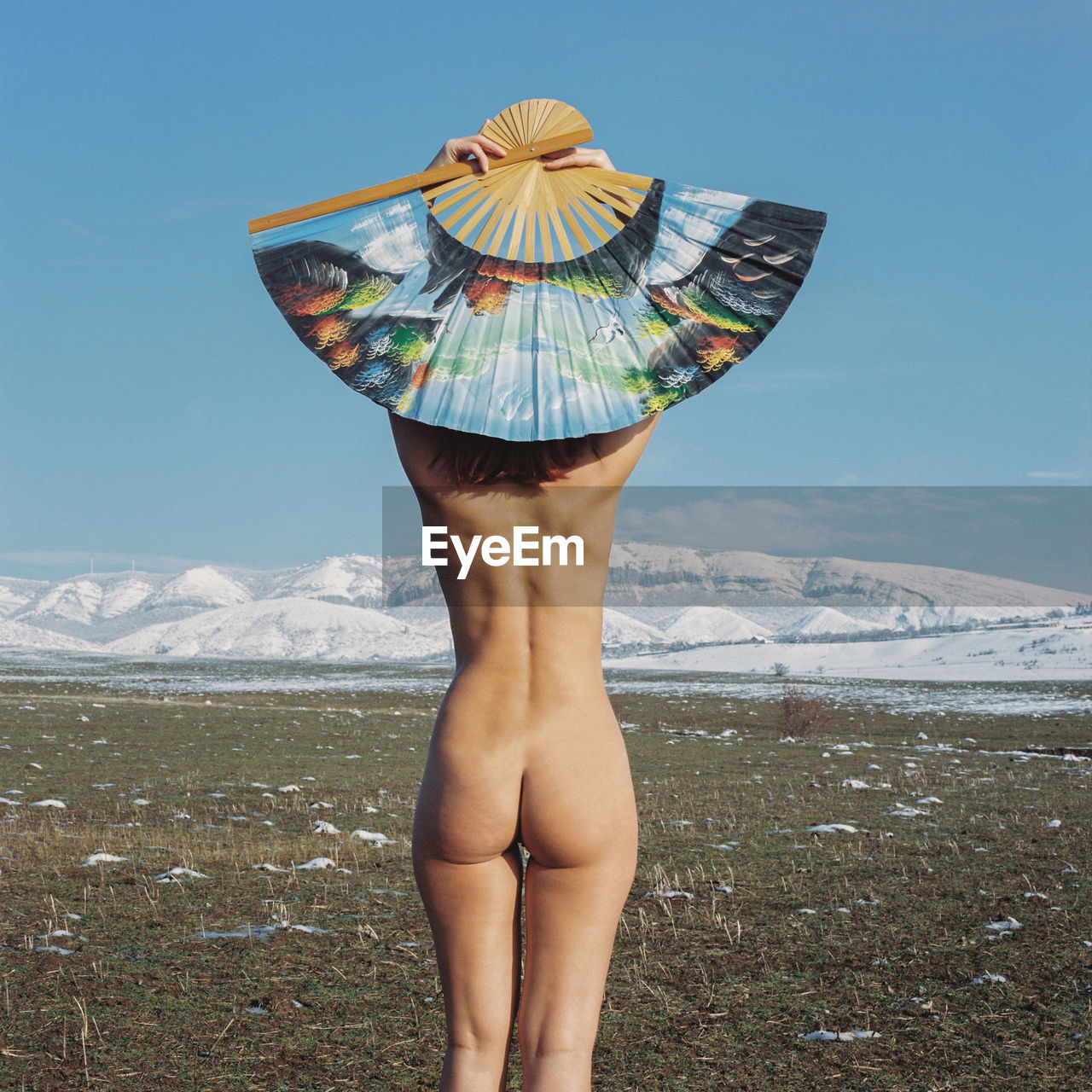 Rear view of naked woman wearing hat looking at snowcapped mountain