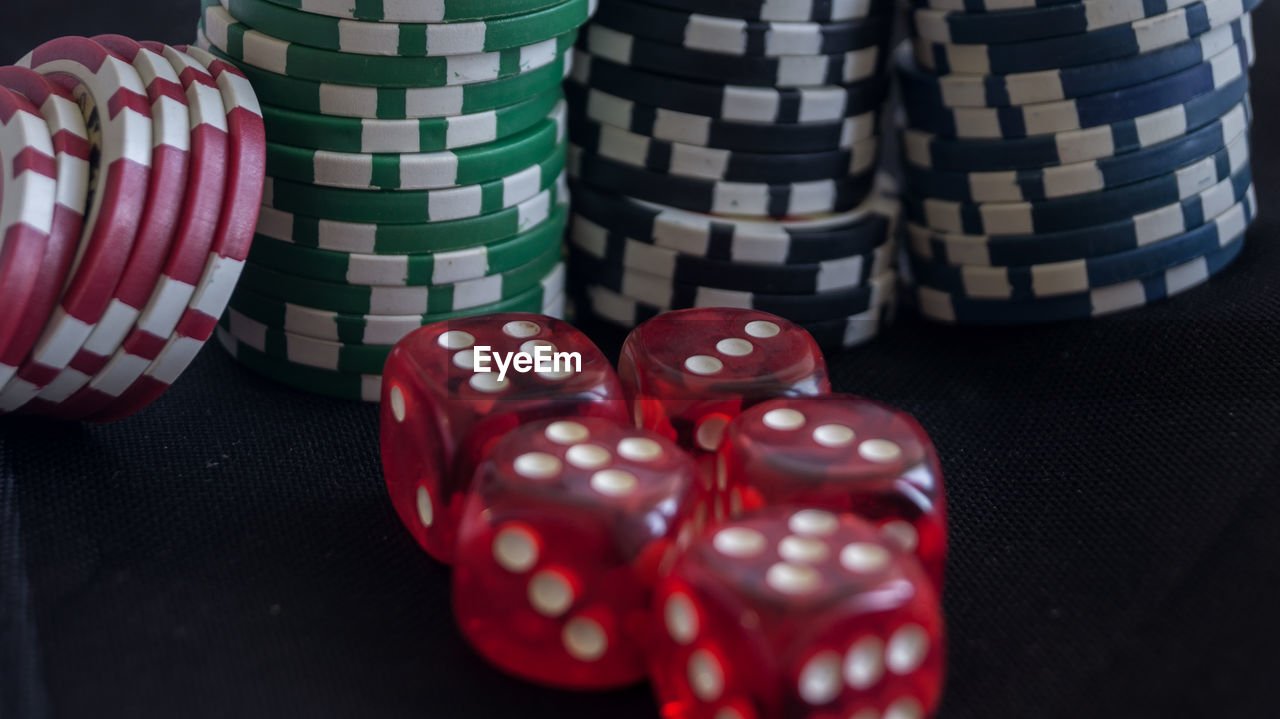 Close-up of red dice and gambling chips on black table