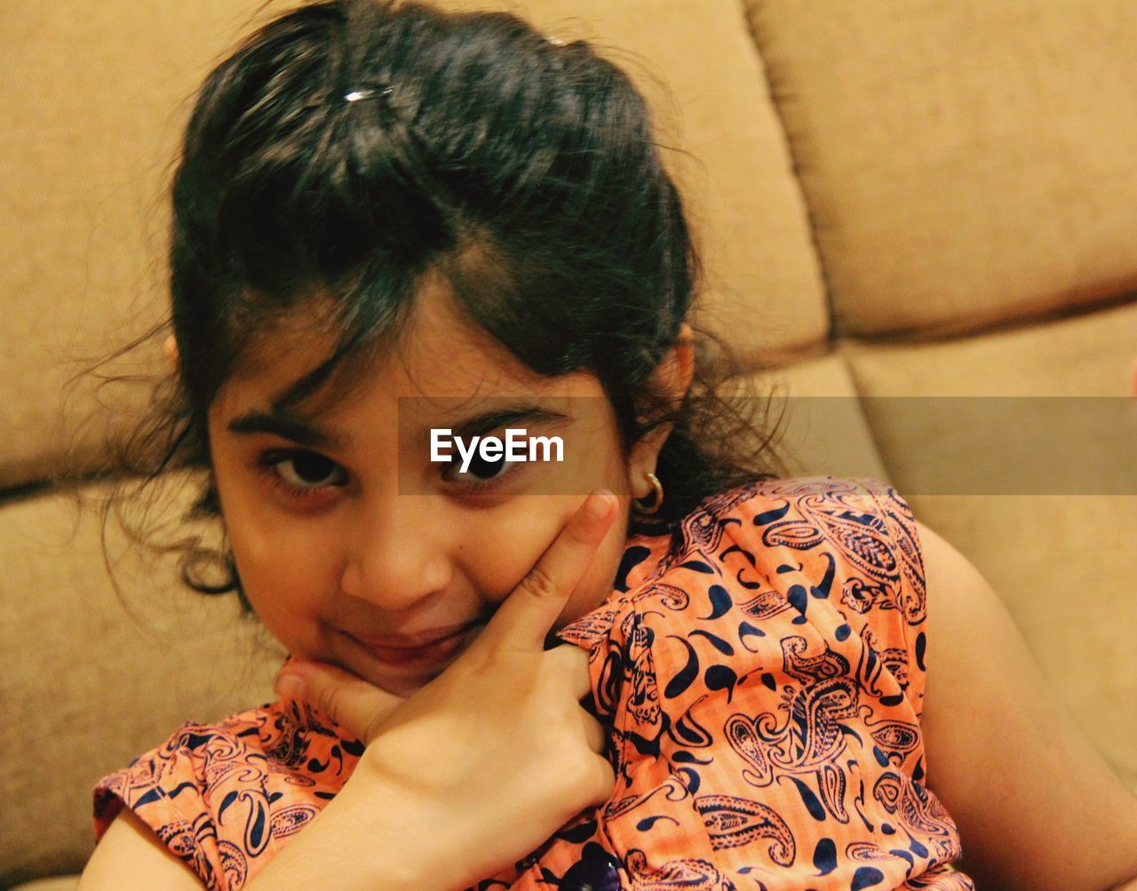 Portrait of girl sitting on sofa at home