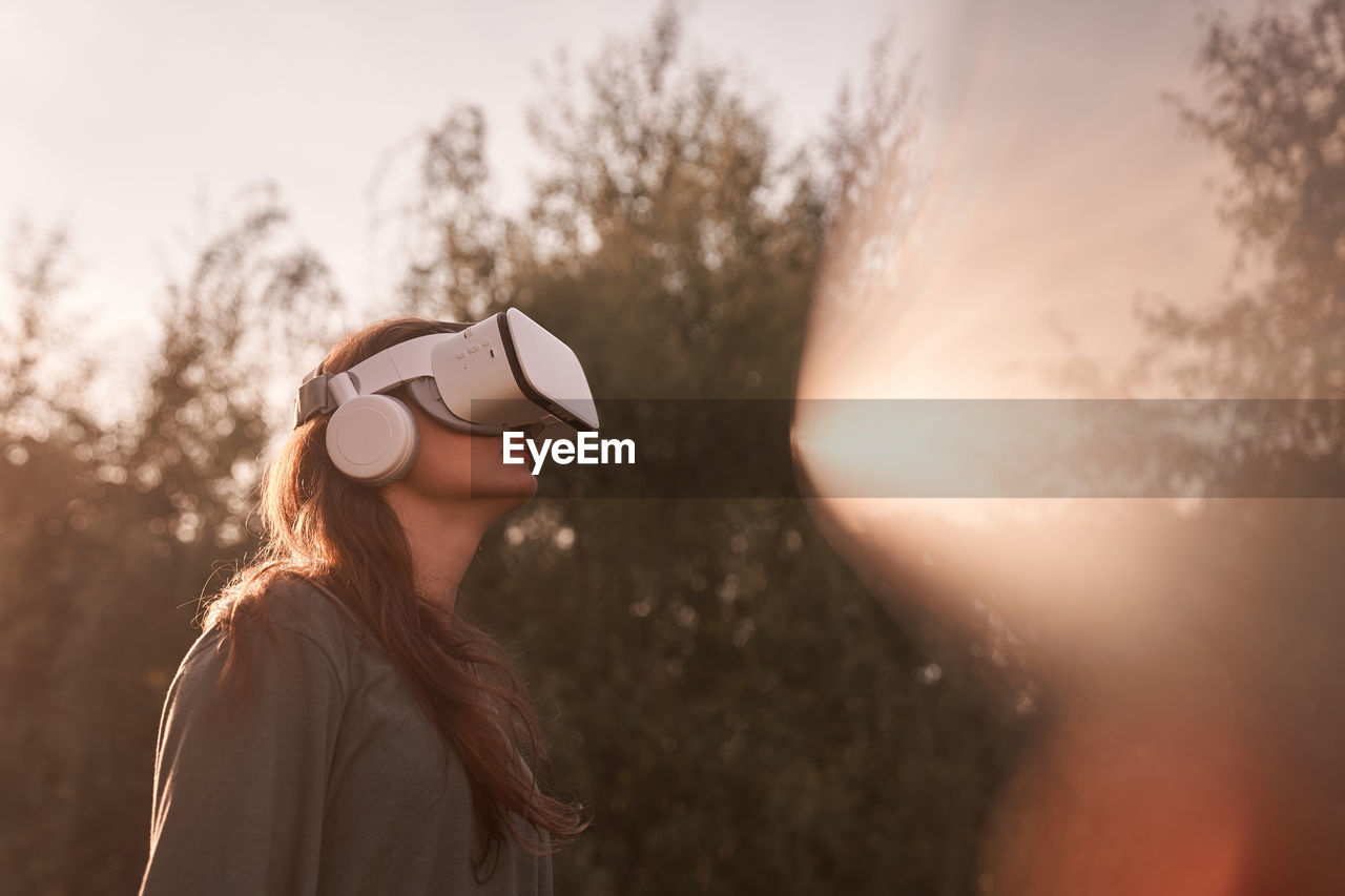 Teenage girl in vr helmet in the park on background of trees