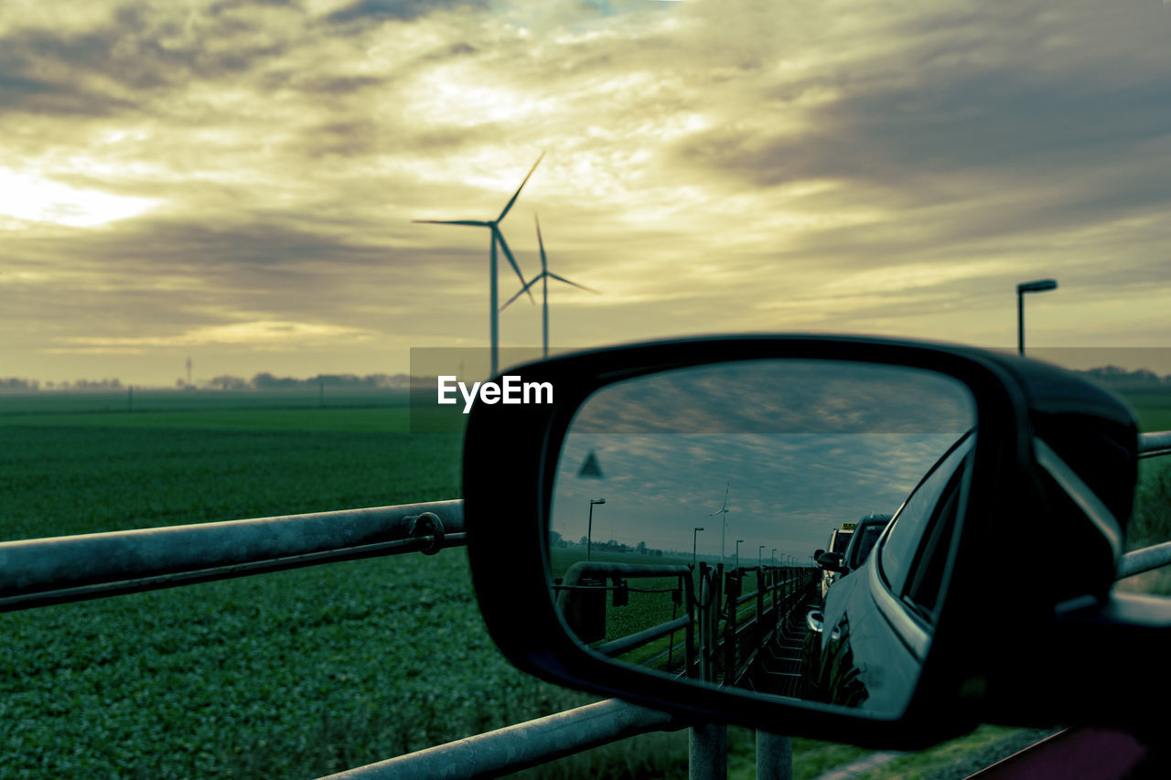 View of side-view mirror against sunset sky