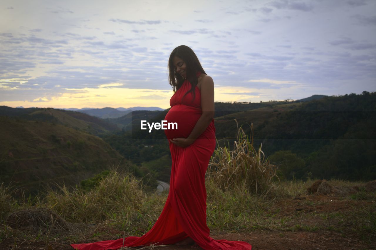 Young woman standing on rock against sky