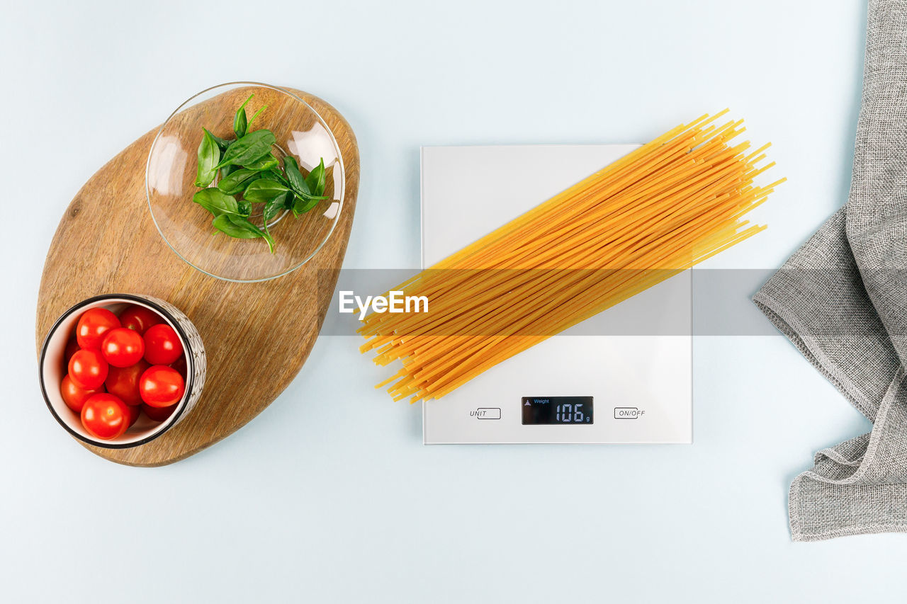 Dry spaghetti on grey digital kitchen scales. flat lay. kitchen equipment. pasta, italian cuisine.