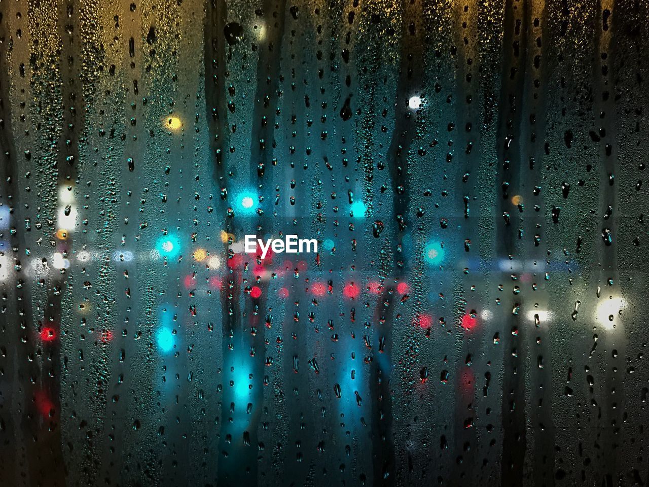 Illuminated lights seen through wet window during rainy season