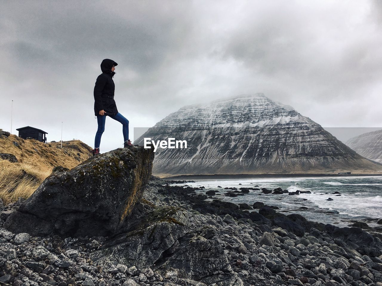 Full length of woman standing on rock against sky at isafjordur