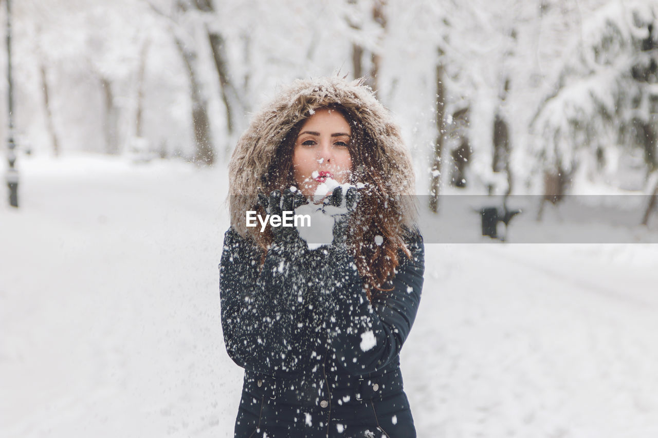 Young woman standing against snow covered tree