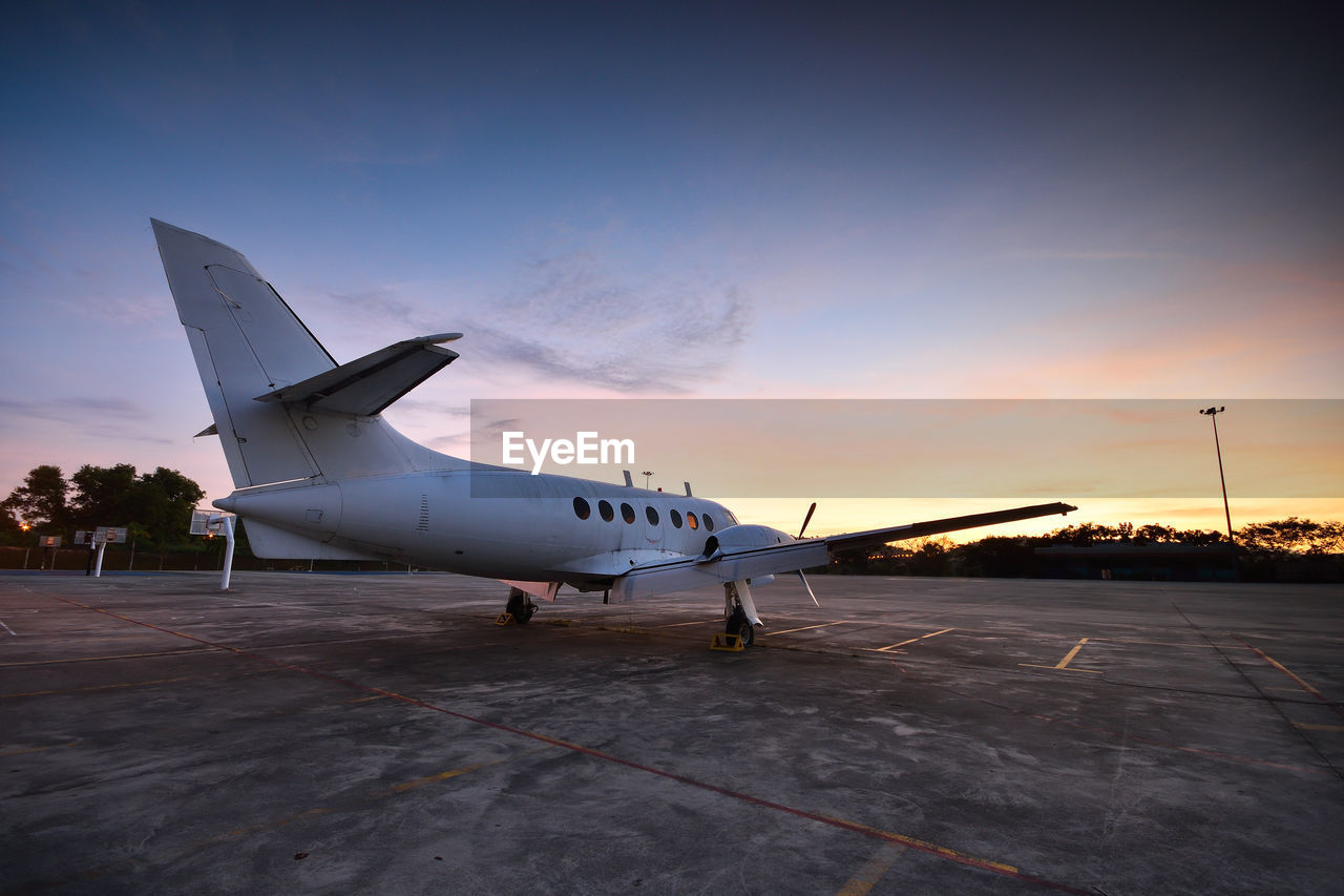 AIRPLANE ON RUNWAY AGAINST SKY DURING SUNSET