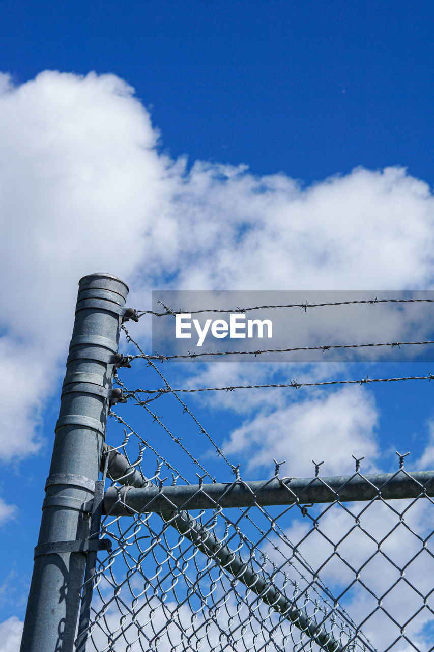 LOW ANGLE VIEW OF CHAINLINK FENCE AGAINST BLUE SKY