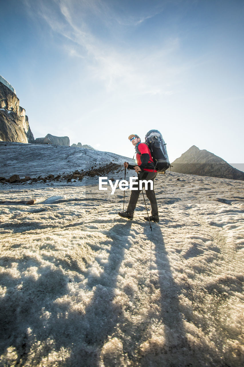 Low angle view of backpacker crossing glacier.