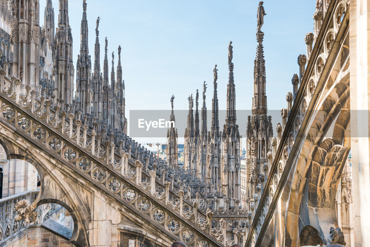 View to spires and statues on roof of duomo through ornate marble fencing. milan, italy