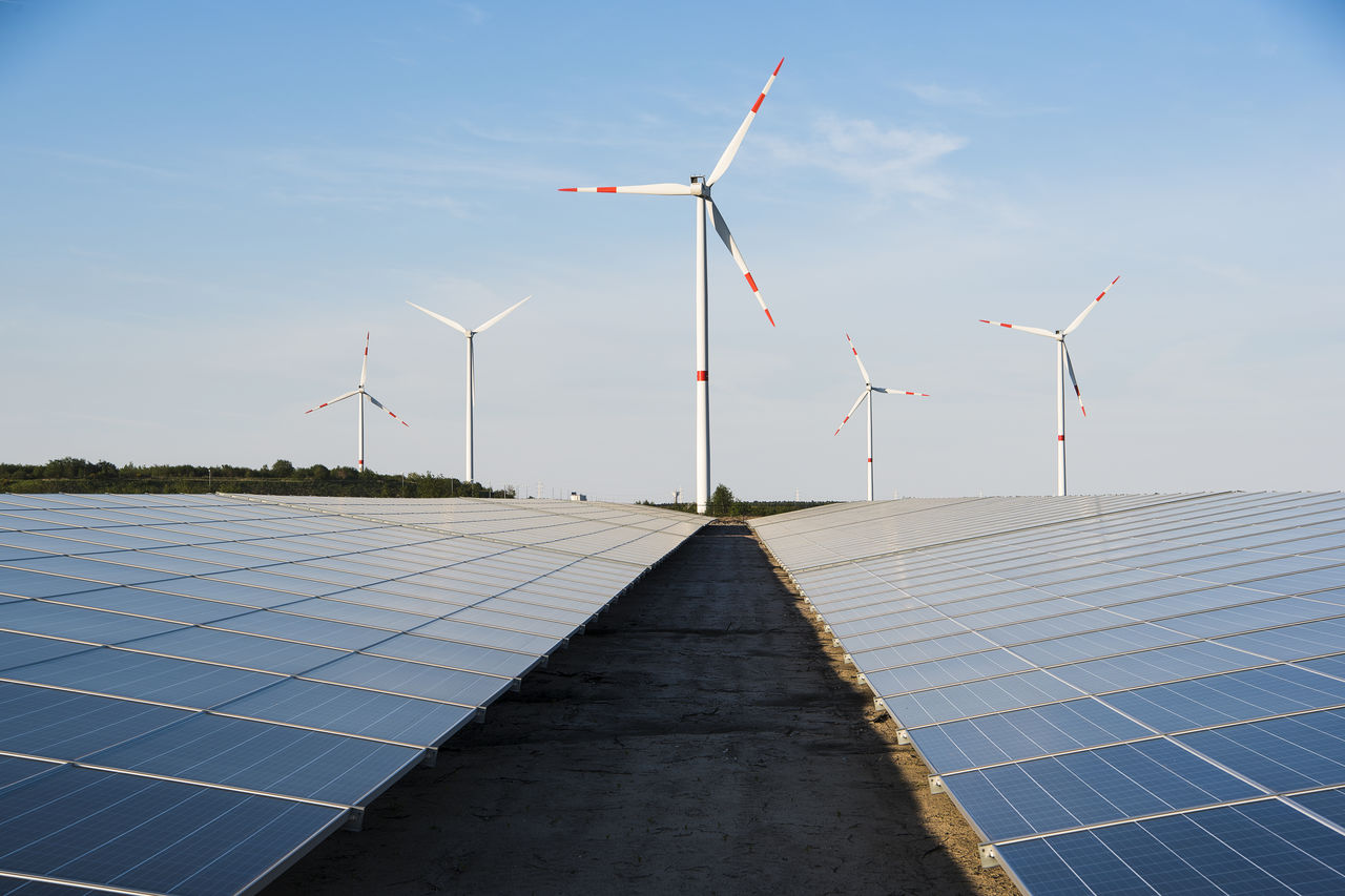 Windmill and solar panels on a blue sky