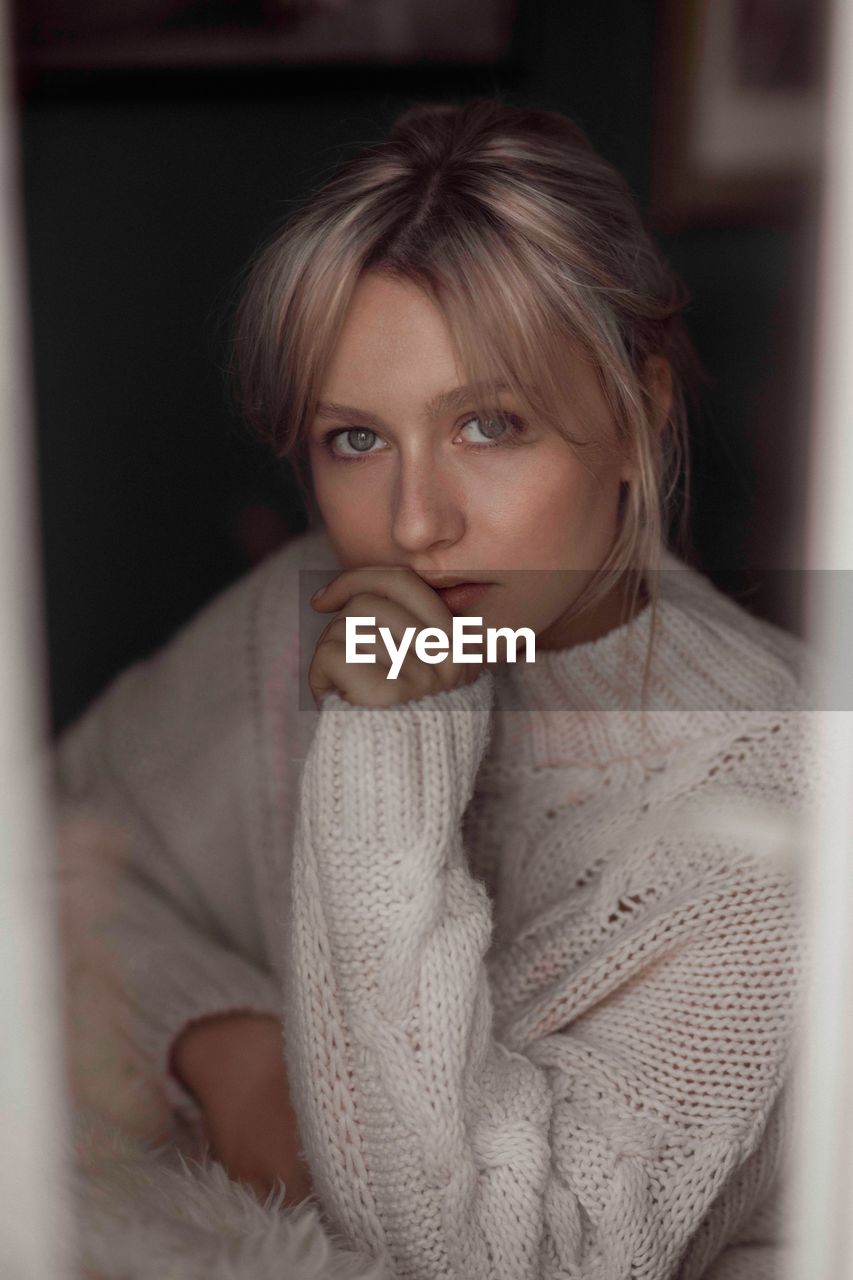 Portrait of beautiful young woman wearing sweater at home