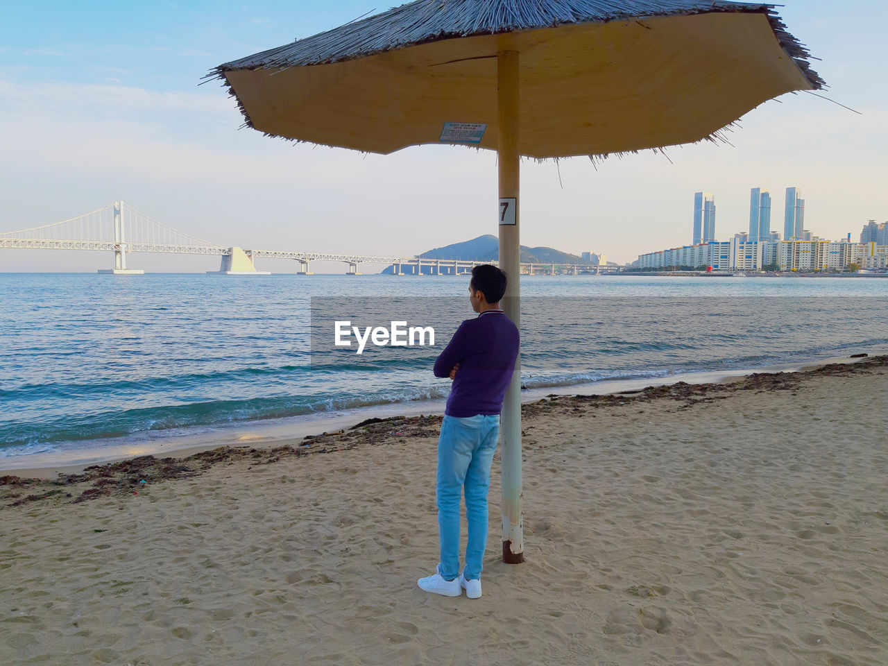 REAR VIEW OF WOMAN STANDING ON BEACH