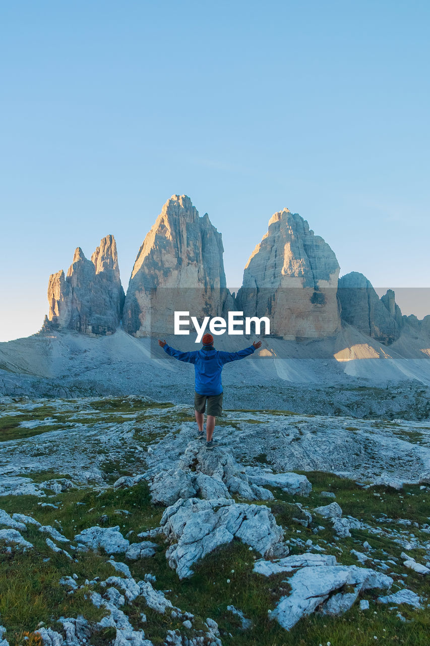 Rear view of person standing on rock against sky