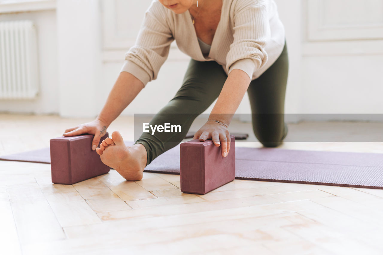 Attractive middle aged woman in sportswear ptactice yoga with equipment in light studio