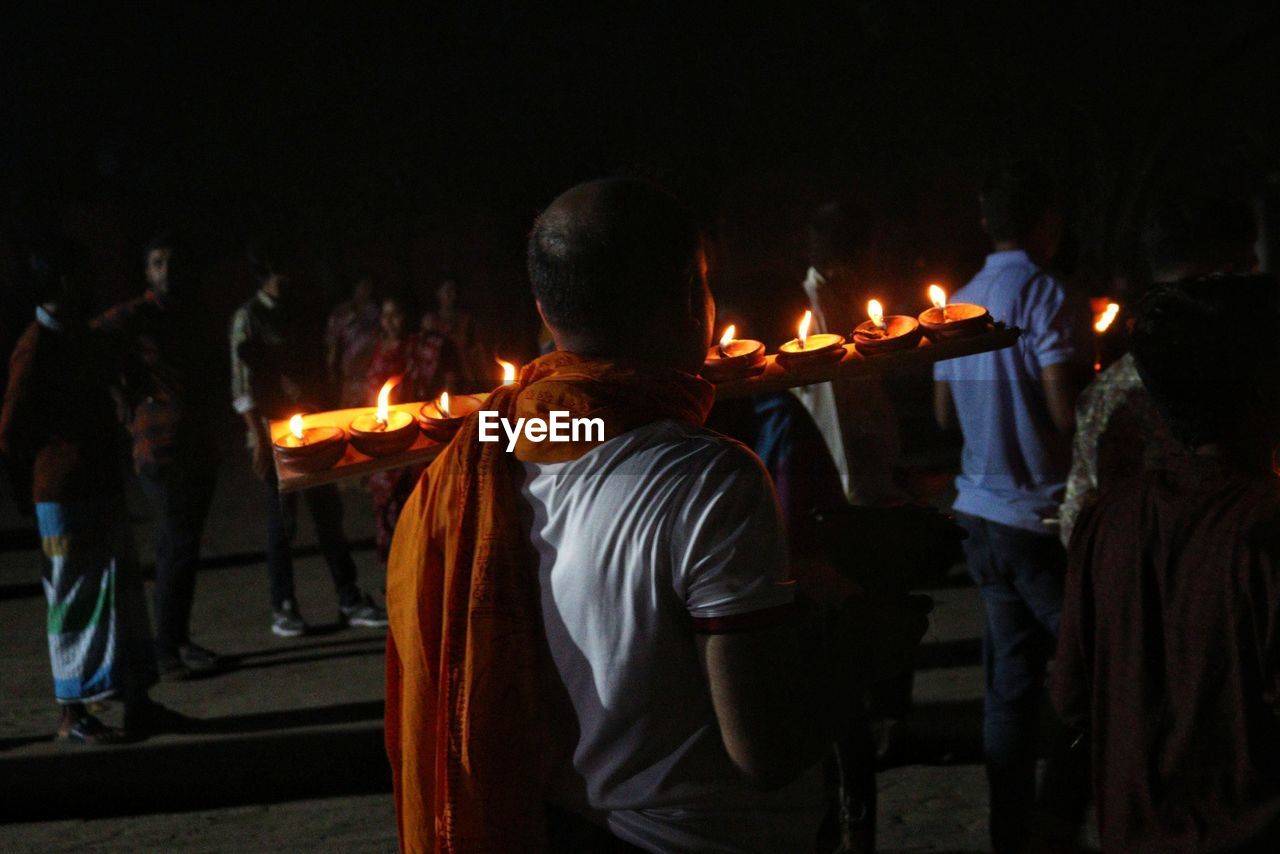 Man walking with dia-oil lamp on hand at rakher upobash inside crowd at rakher upobash baradi