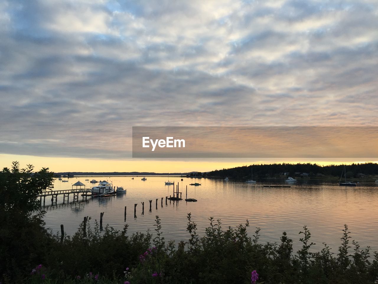 Scenic view of lake against cloudy sky during sunset