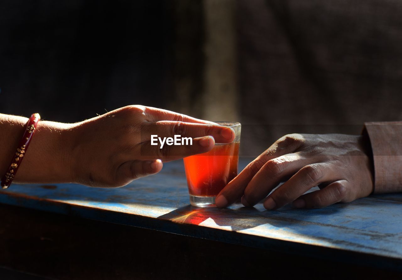 Close-up of hand holding drink on table