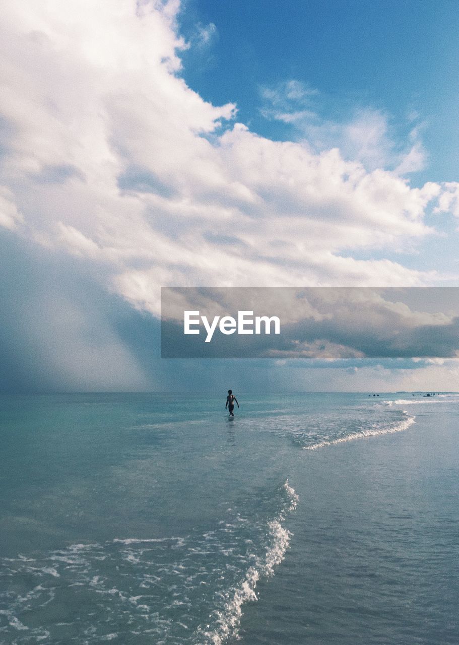 Mid distance view of person on shore at beach against sky