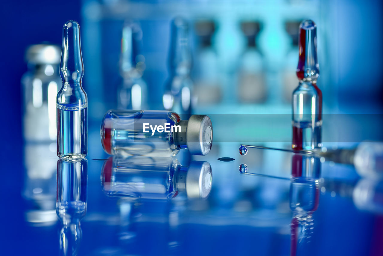 Close-up of syringe against blue background - vaccination