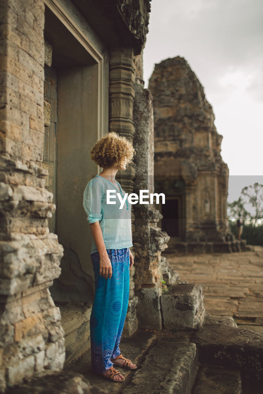 Side view of mid adult woman standing at angkor wat entrance