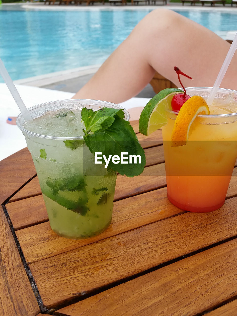 Cocktails on wooden table with swimming pool in background