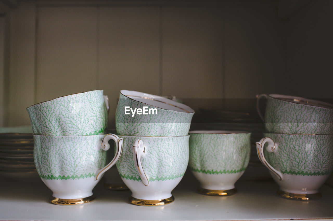 Stack of teacups in shelf at home