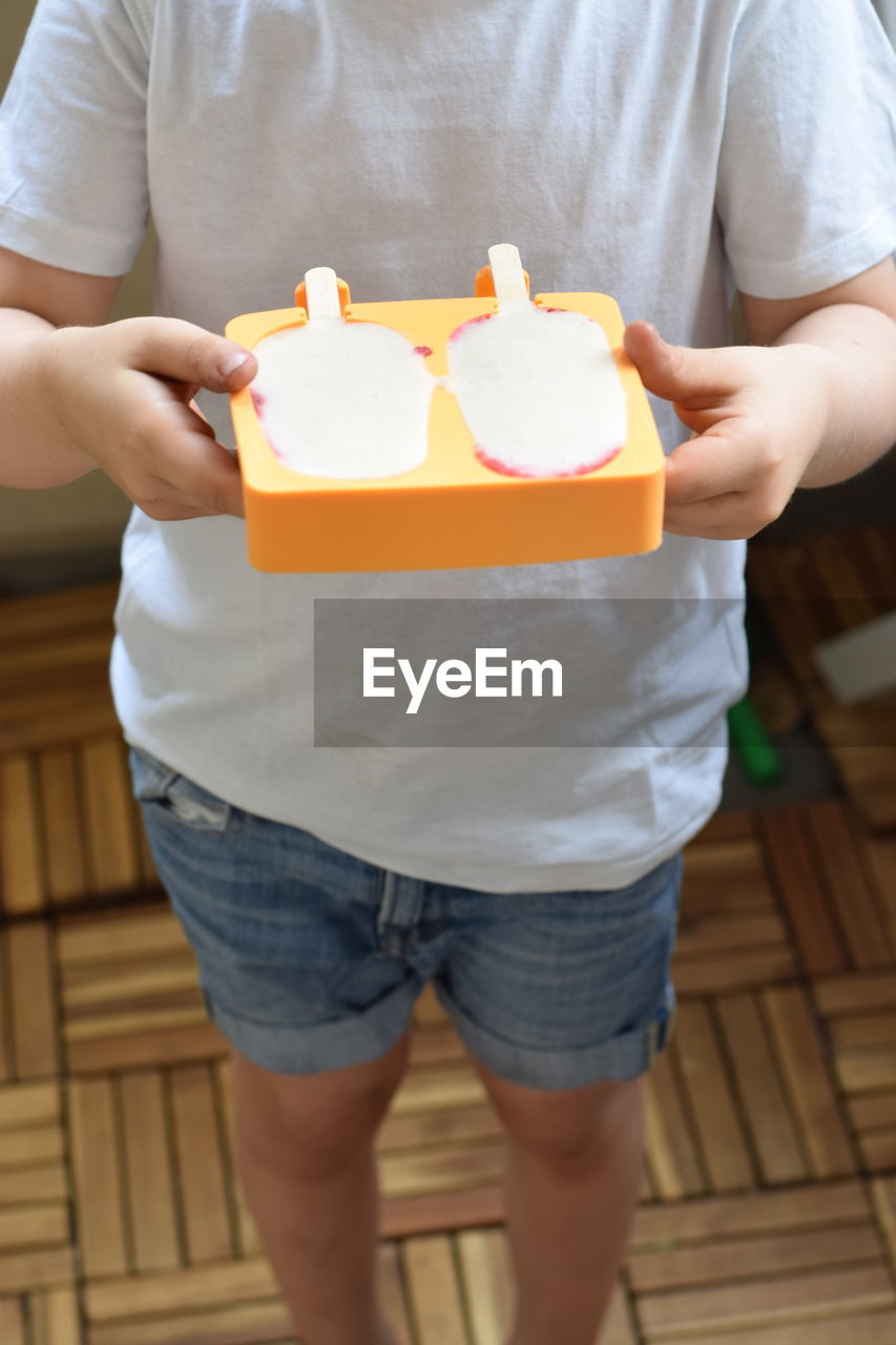 Close-up of a boy holding ice creams in molds