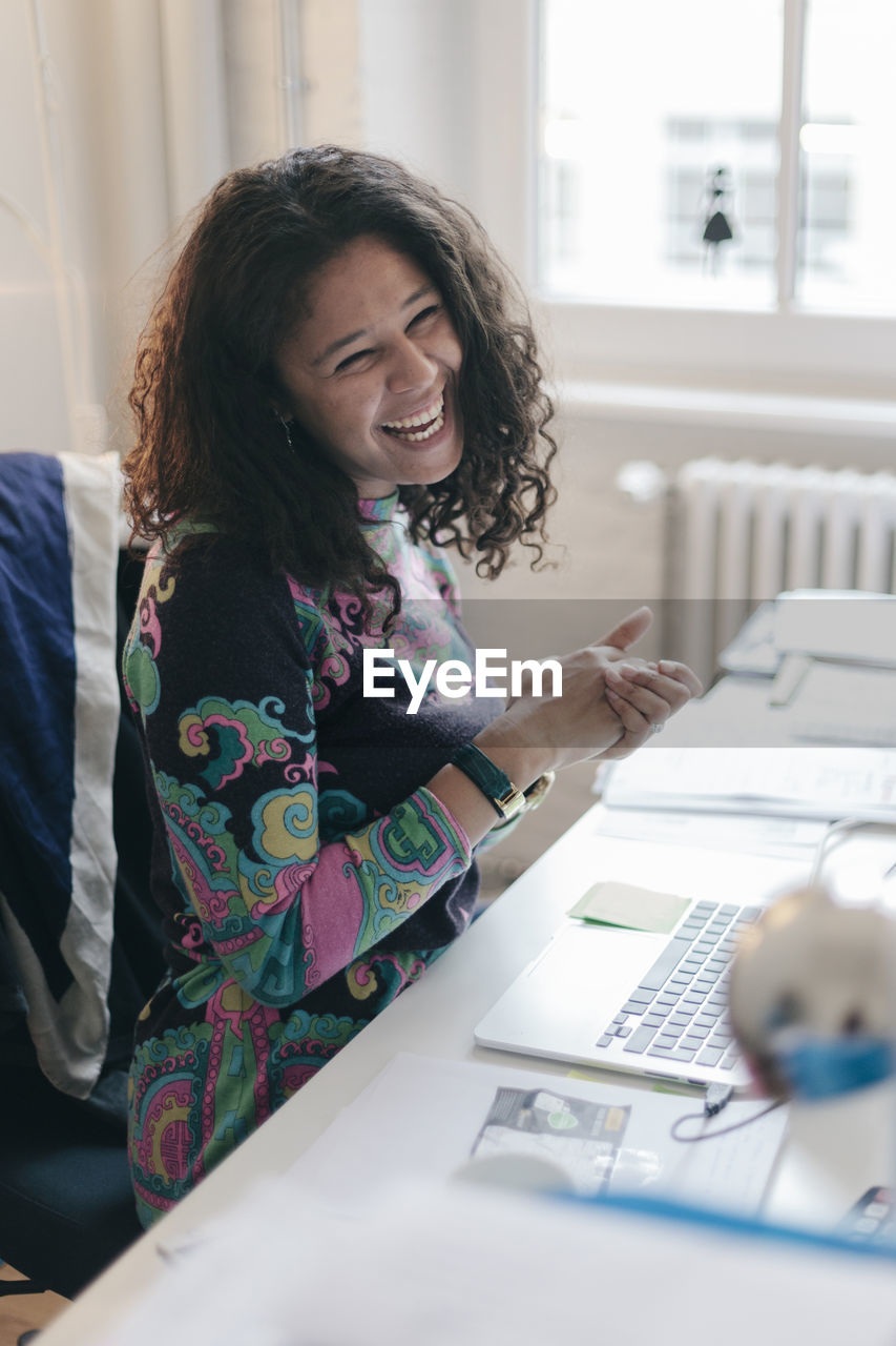 Happy young businesswoman using laptop in office