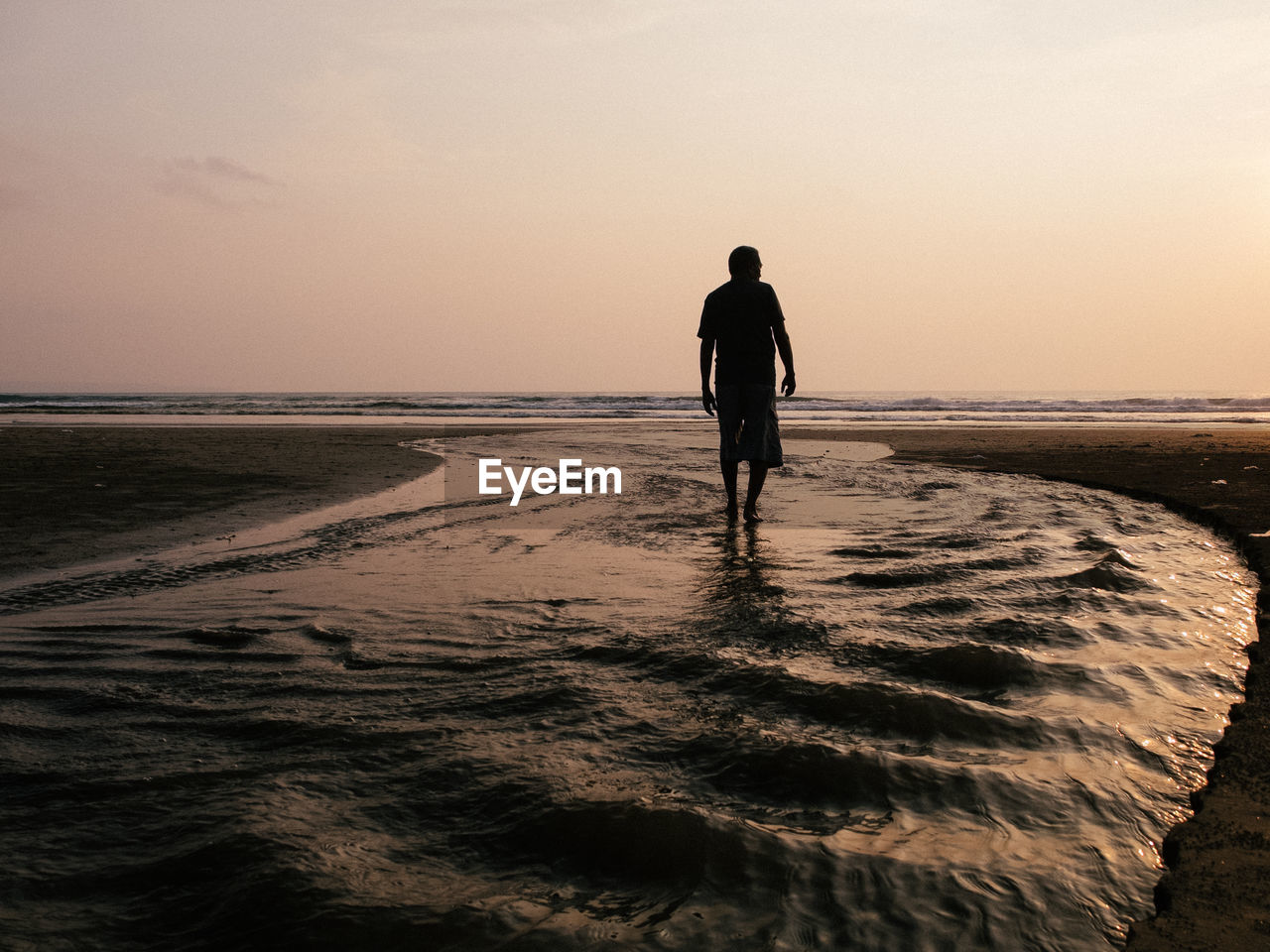 Silhouette man standing on beach against clear sky