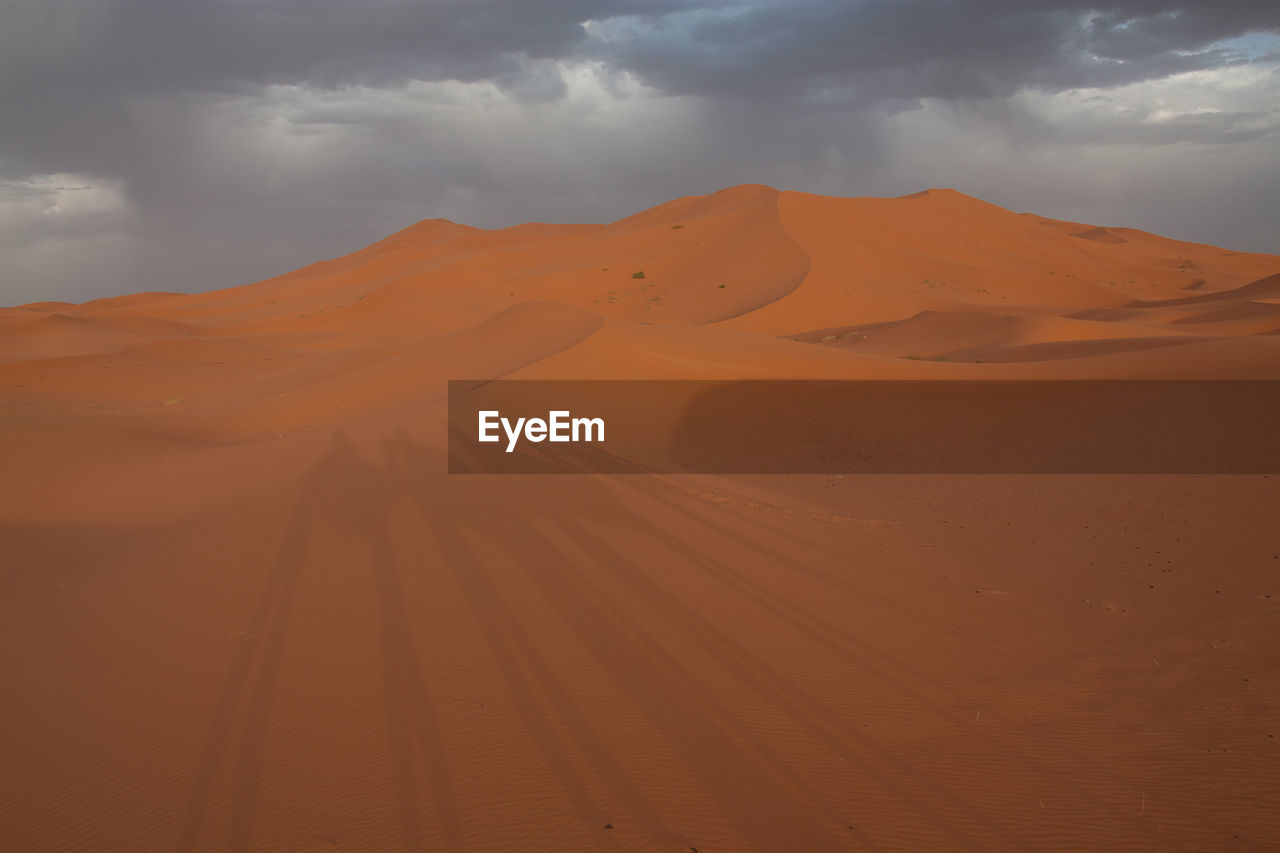 Scenic view of desert land against cloudy sky