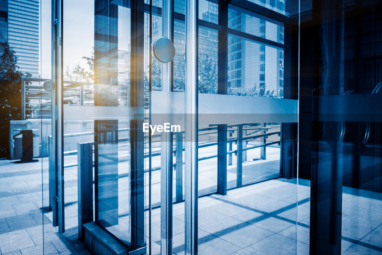 REFLECTION OF MODERN BUILDING ON GLASS WINDOW