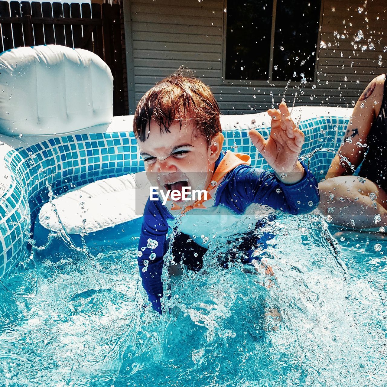 Cute cheerful boy playing at wading pool