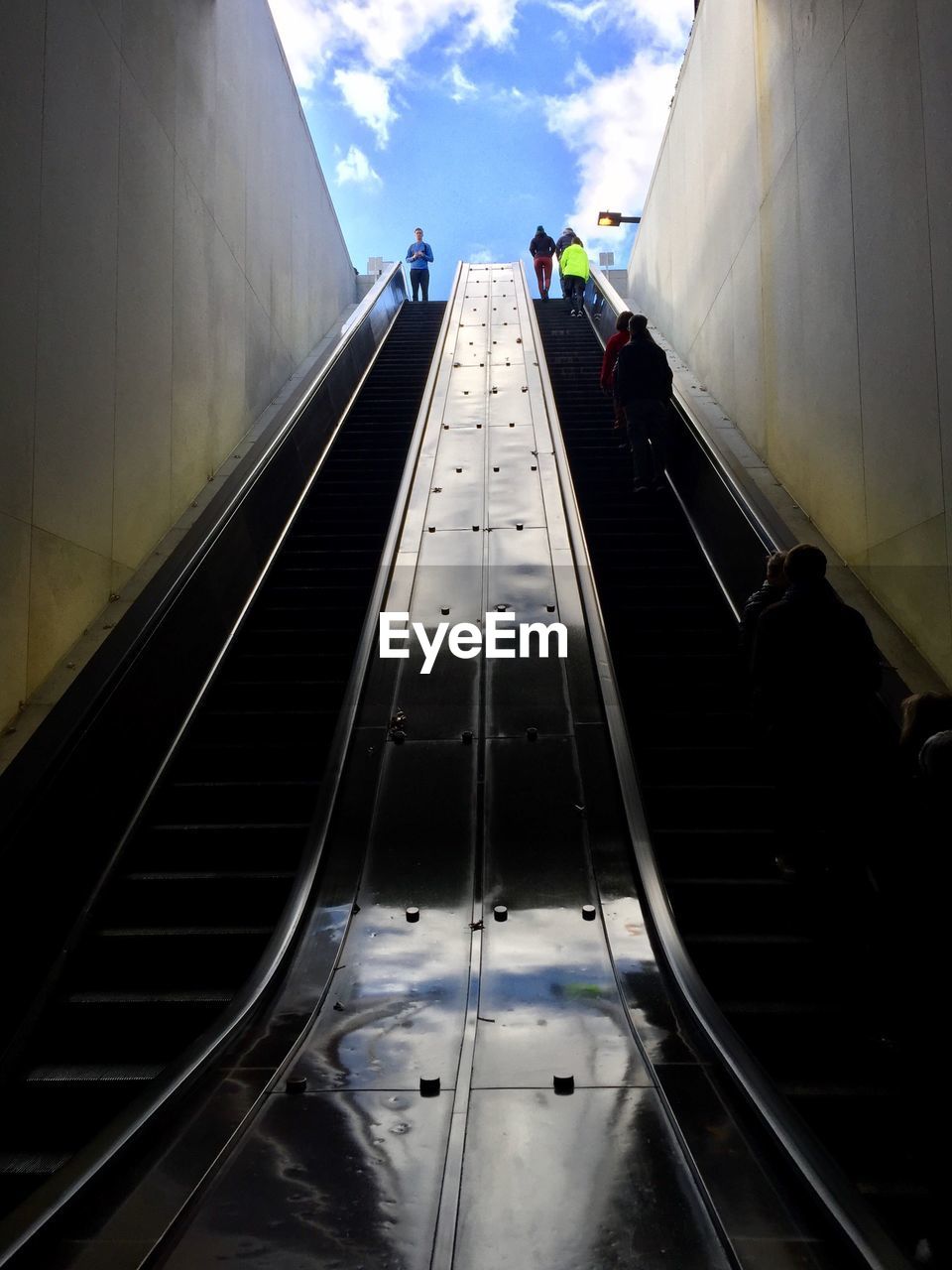 People traveling on escalator against sky