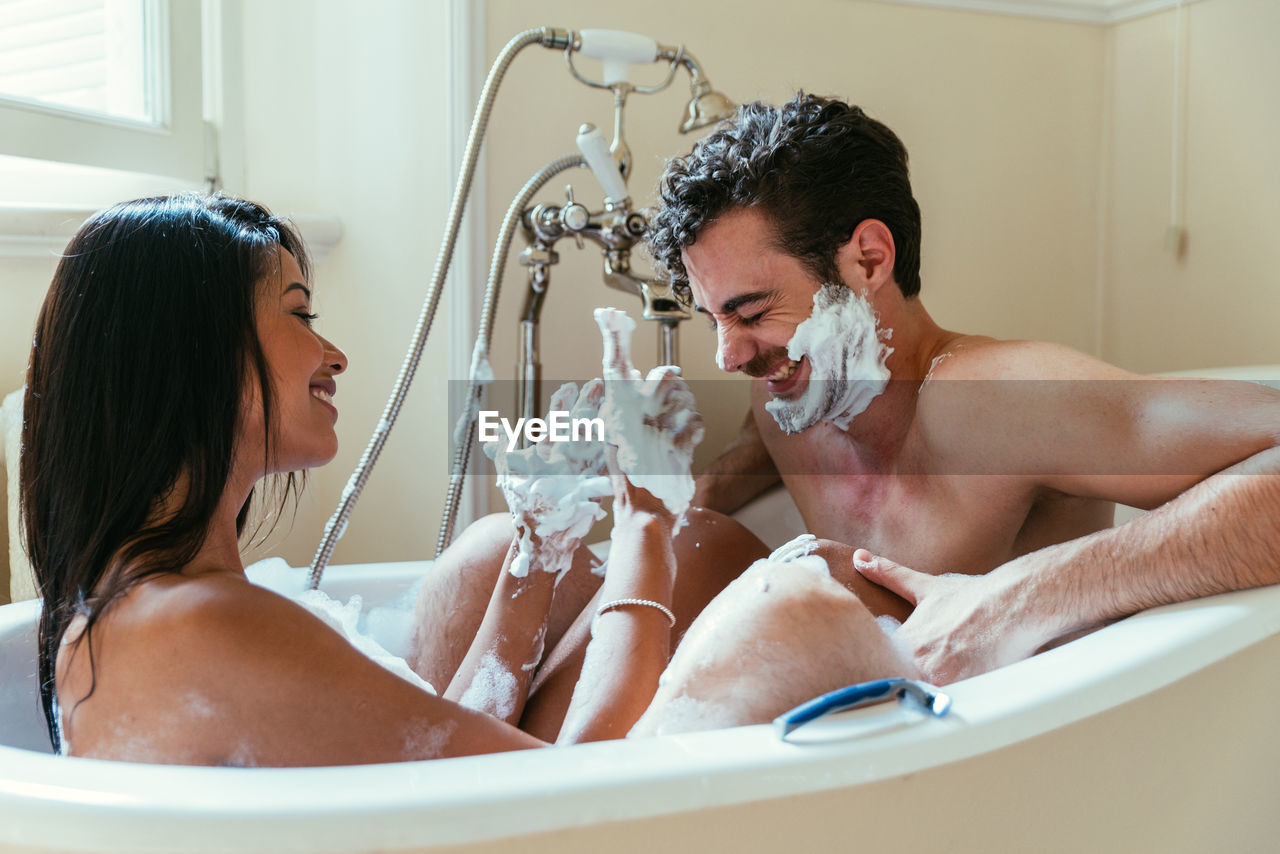 Woman applying shaving cream on boyfriend face