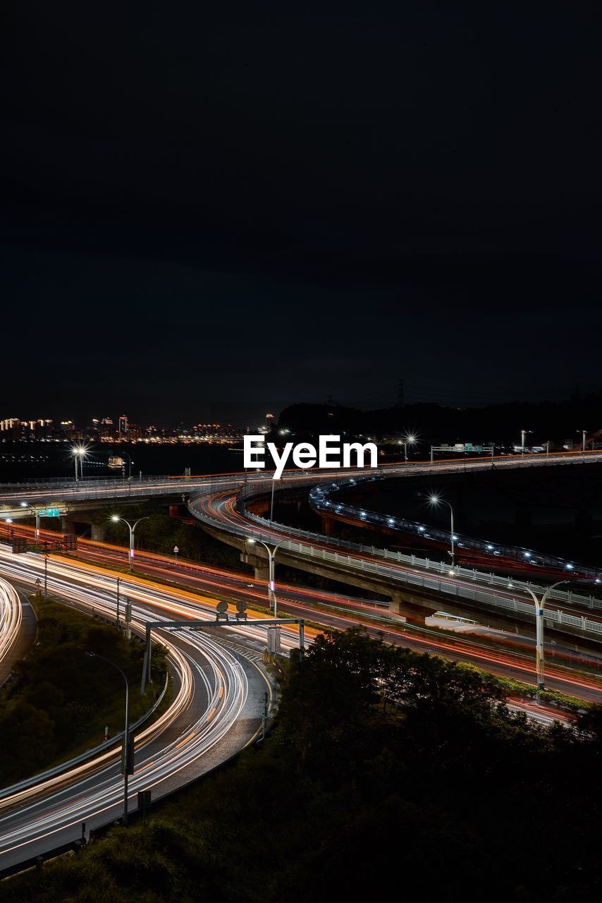 Light trails on road in city against sky at night