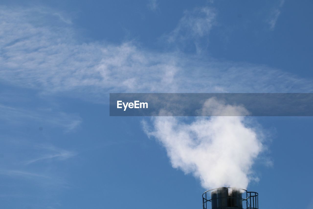 Low angle view of smoke emitting from chimney against sky