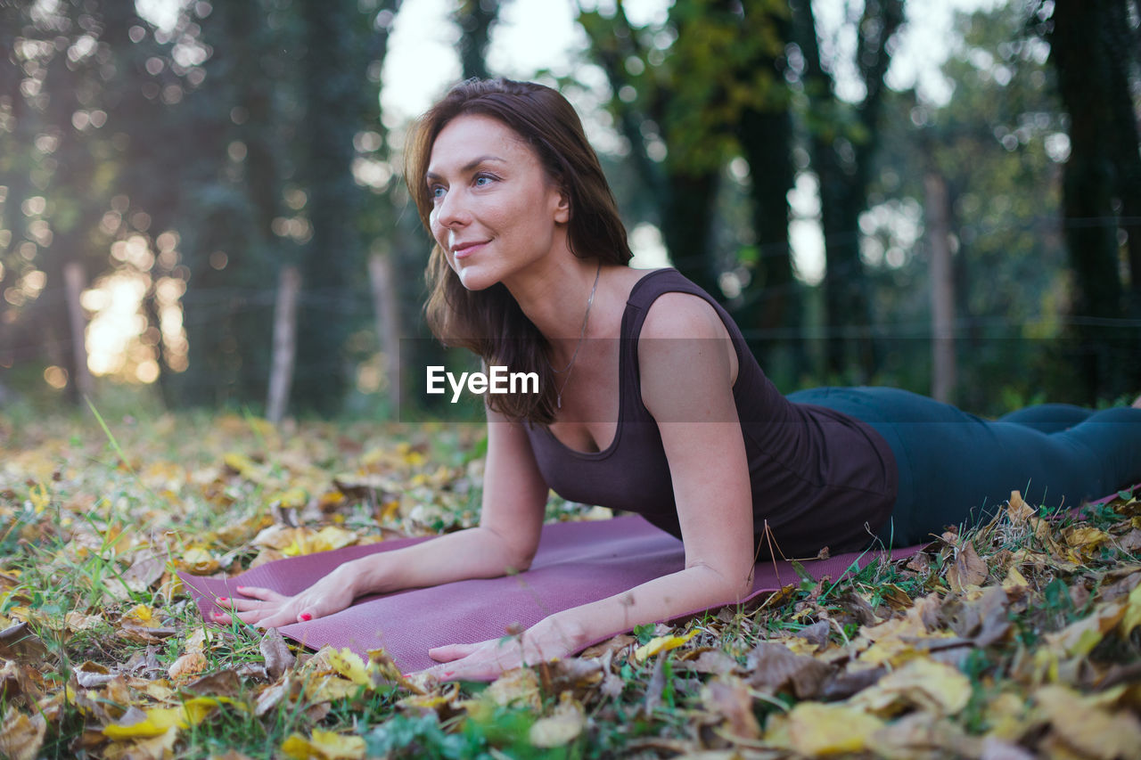 Woman exercising while lying down by tree at park