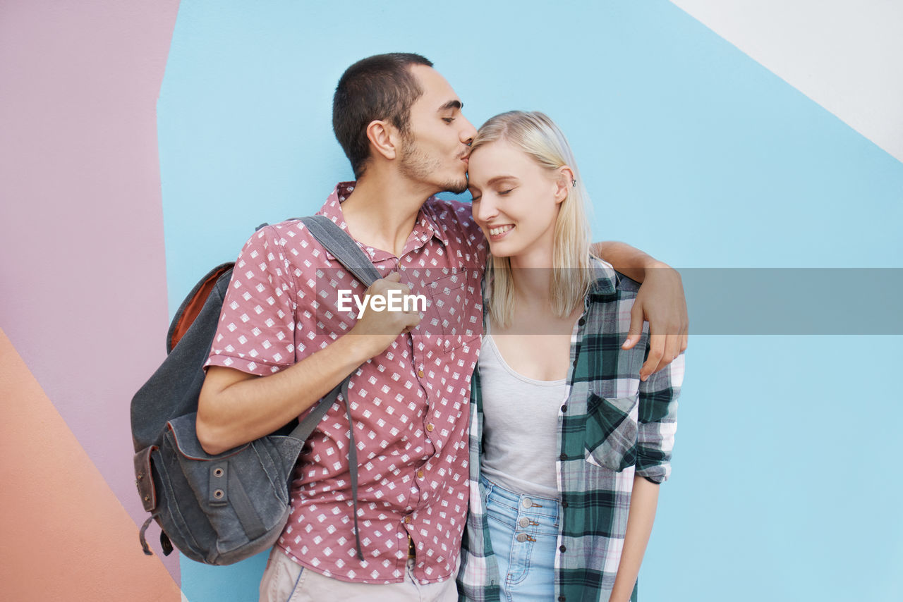 Young couple embracing against wall