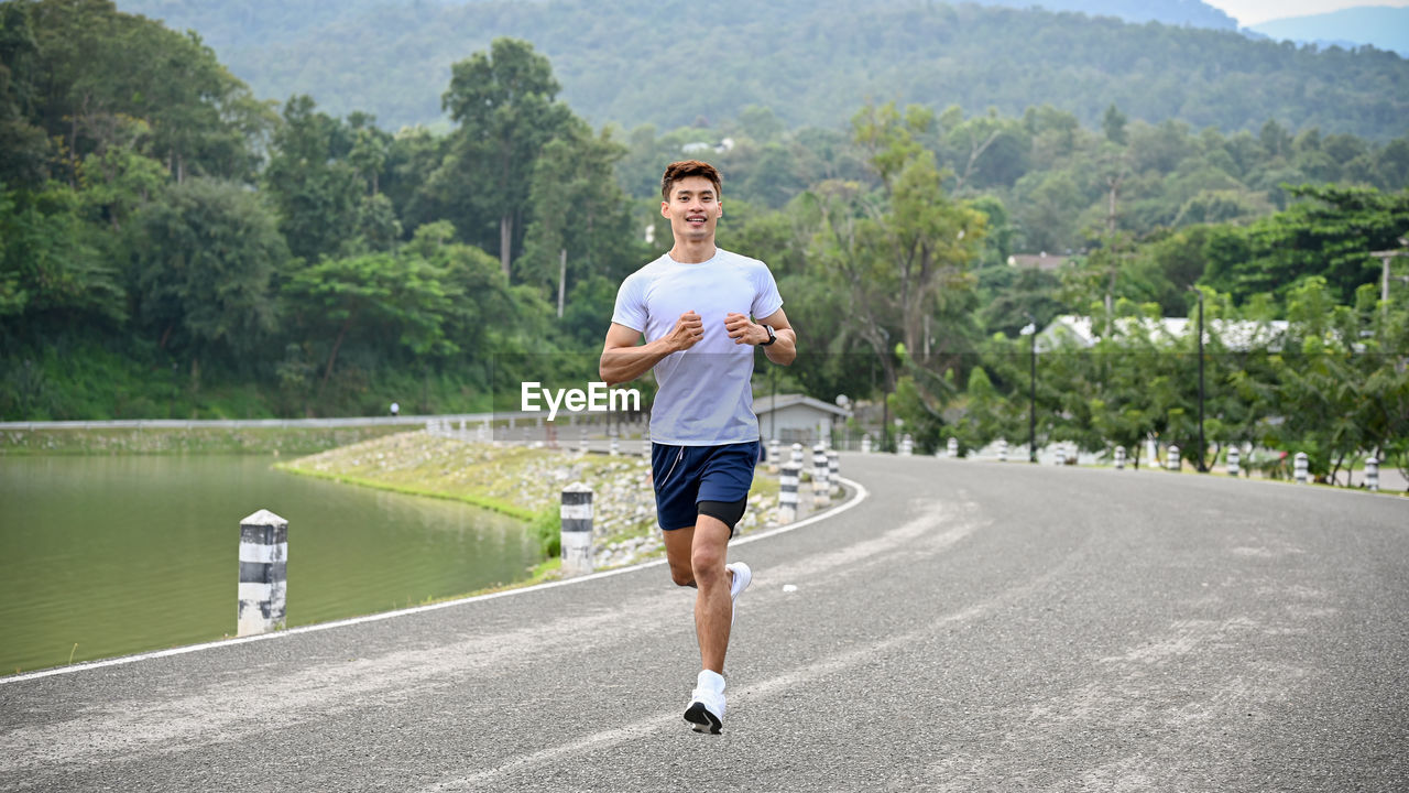 sports, one person, person, recreation, exercising, lifestyles, sports clothing, running, full length, adult, jogging, nature, clothing, athlete, day, road, transportation, men, plant, tree, leisure activity, motion, young adult, vitality, individual sports, front view, shorts, player, sports training, casual clothing, outdoors, activity, water, endurance, determination, long distance running, running shorts, city