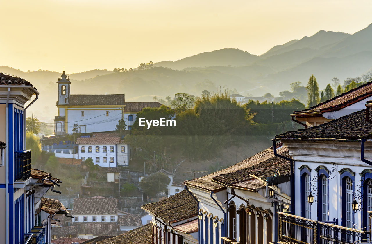 View of old colonial style city of ouro preto with houses, churches and hills at sunset