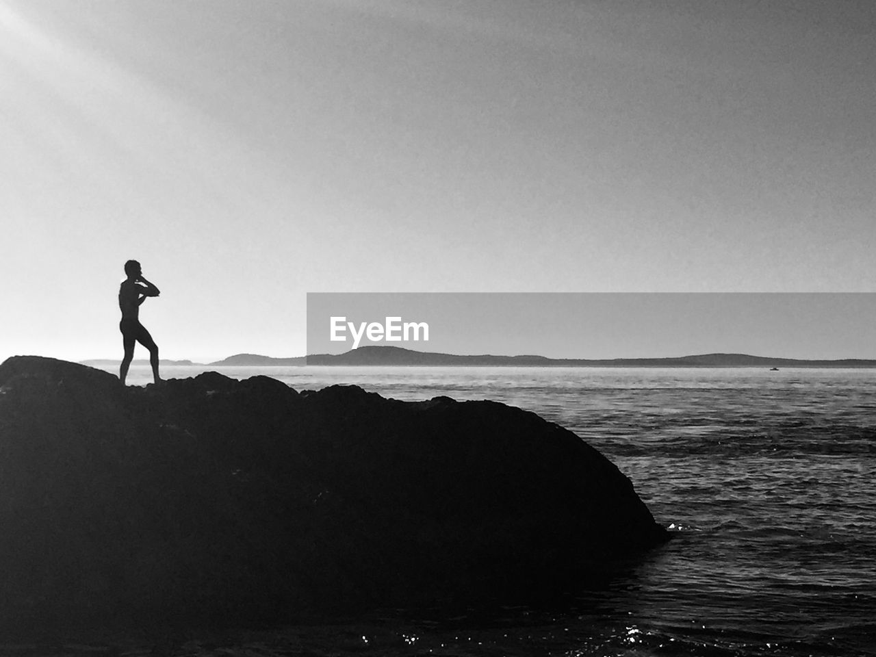 SILHOUETTE PERSON STANDING ON ROCK AGAINST SEA