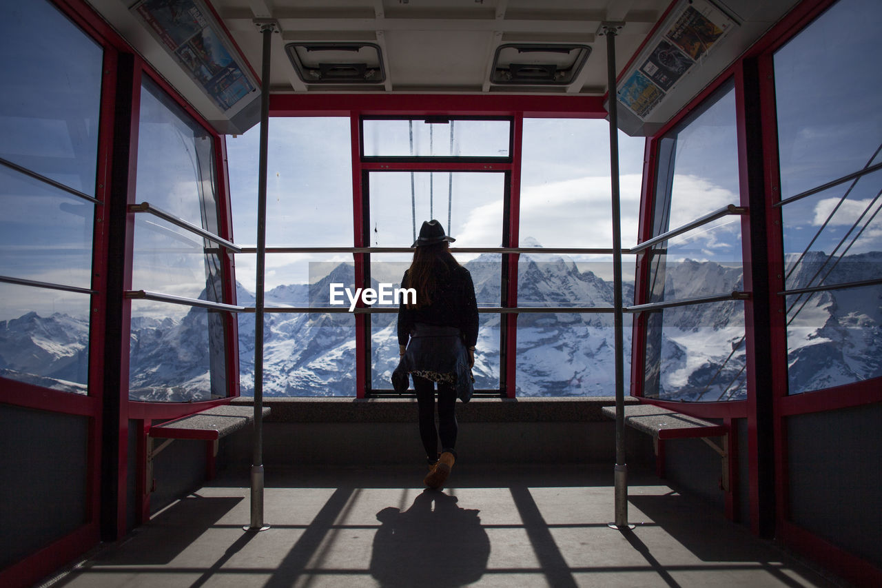 Rear view of women looking towards snowcapped mountains through ski lift windows