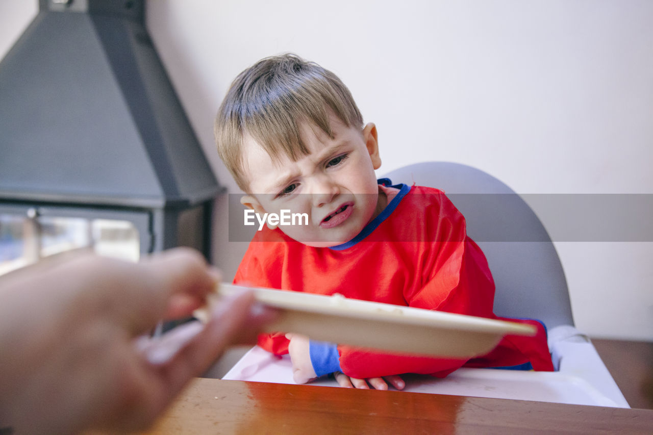 Cute boy crying while sitting on high chair