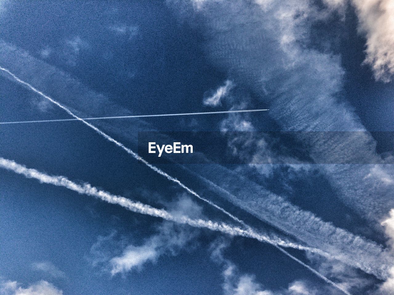 LOW ANGLE VIEW OF VAPOR TRAILS IN BLUE SKY